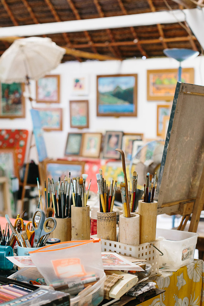 Paint brushes and pastels sit on the desk of an artists studio