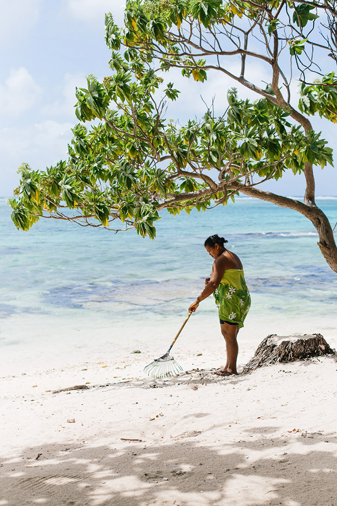 A local Tahitian woman sweeps on the beach