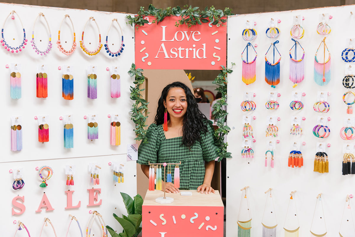 Love Astrid designer poses for a portrait with their stand