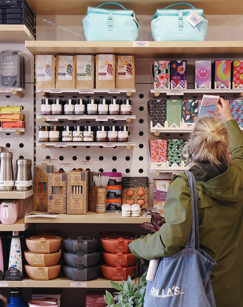 A customer reaches to pick out a bar of chocolate on the shelf of a brick and mortar store stocking an array of homewares and eco friendly products in Melbourne