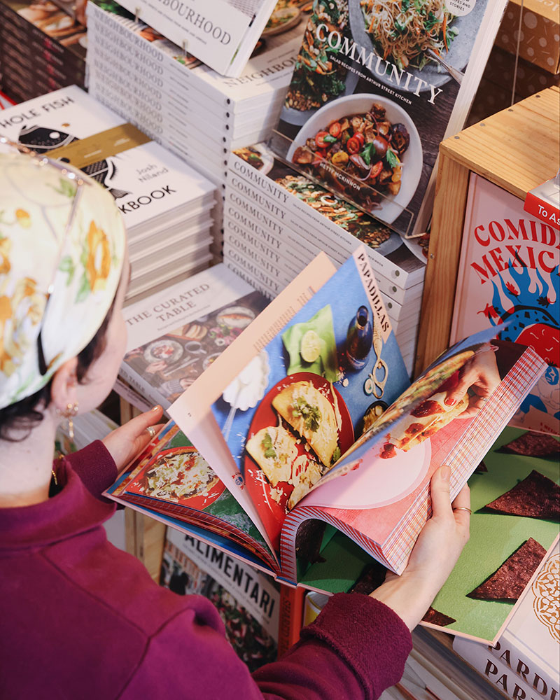 A customer flicks through a colourful cookbook at A Quirk of Fate