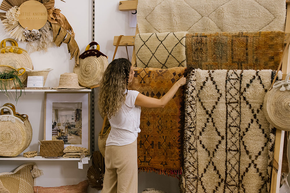 Female founder of Little Known Makers rugs sourced from Morocco adjusts her stand display
