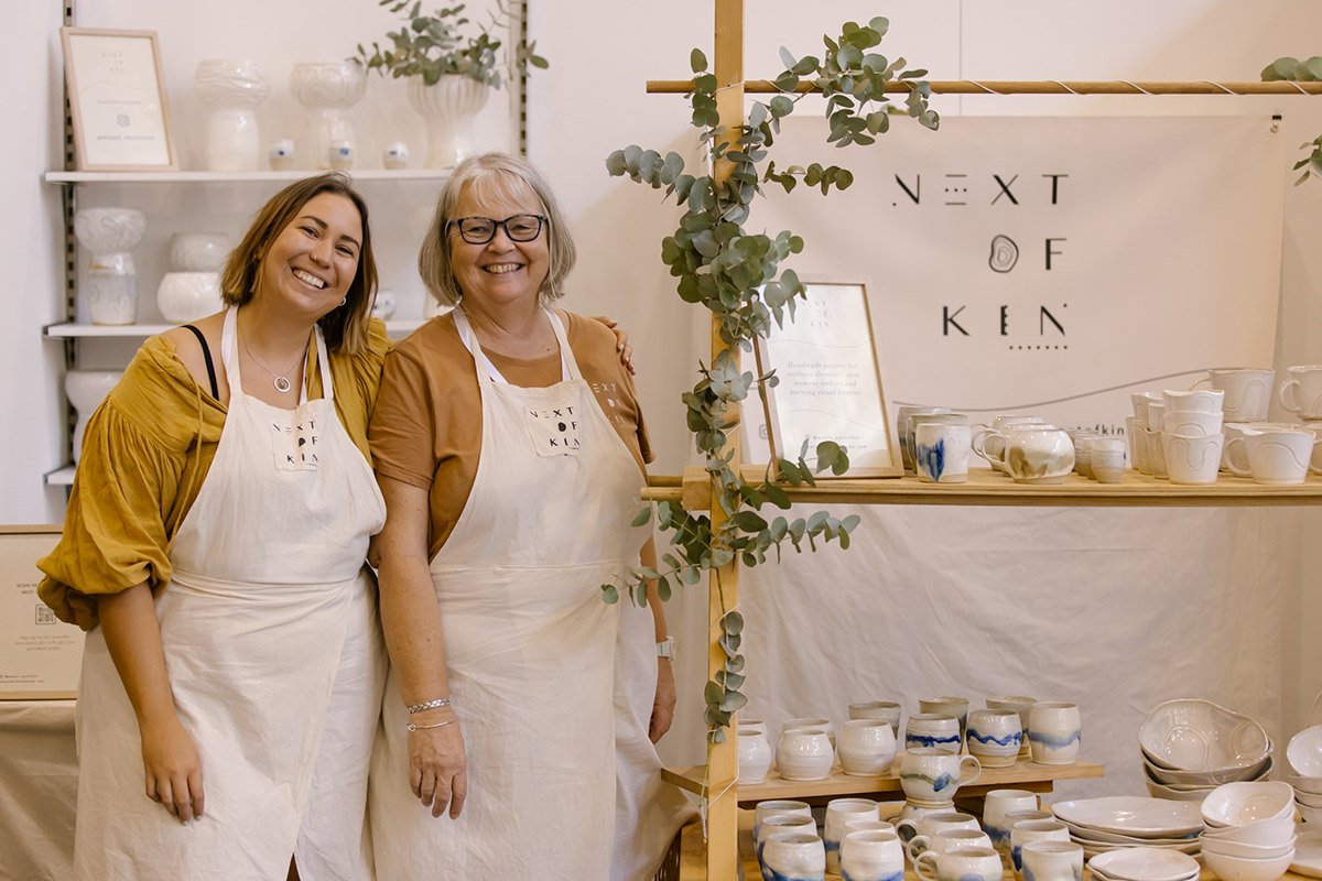 Mother daughter duo of ceramics label Next of Kin pose for a photo in front of their stand