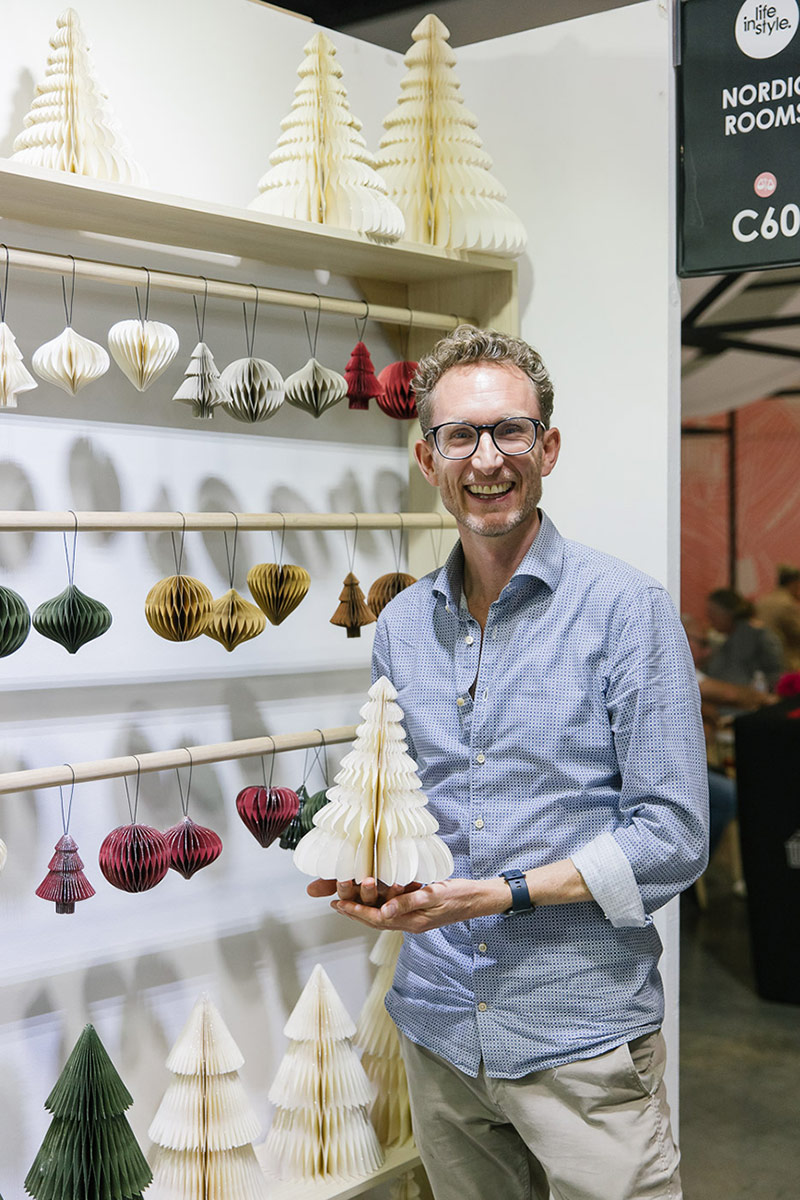 A male exhibitor poses for a portrait with their Christmas products and display ornaments