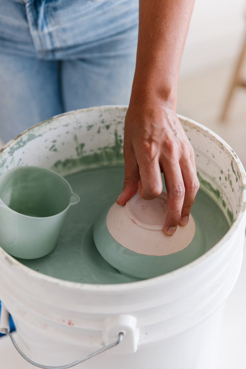 Bisque fired ceramic works are dipped into glaze buckets before their final firing