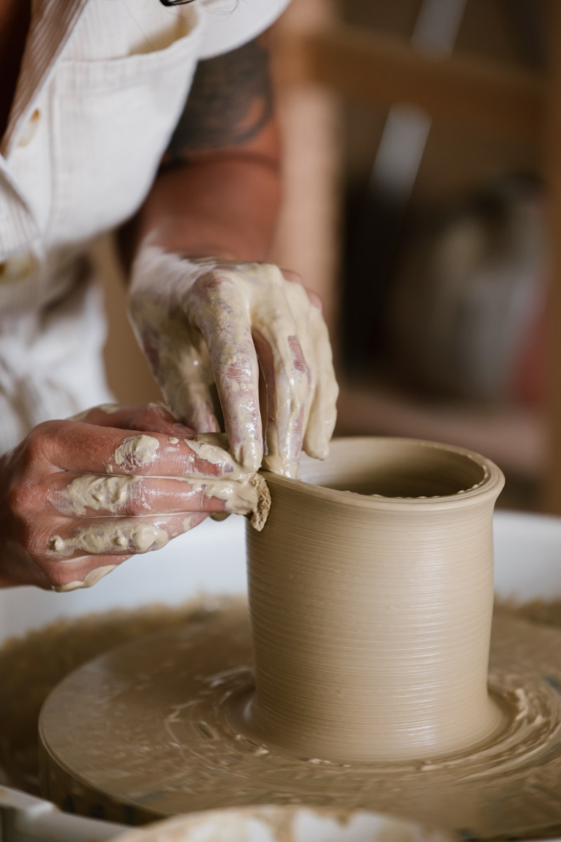 Pulling up clay on the pottery wheel to create a straight vessel