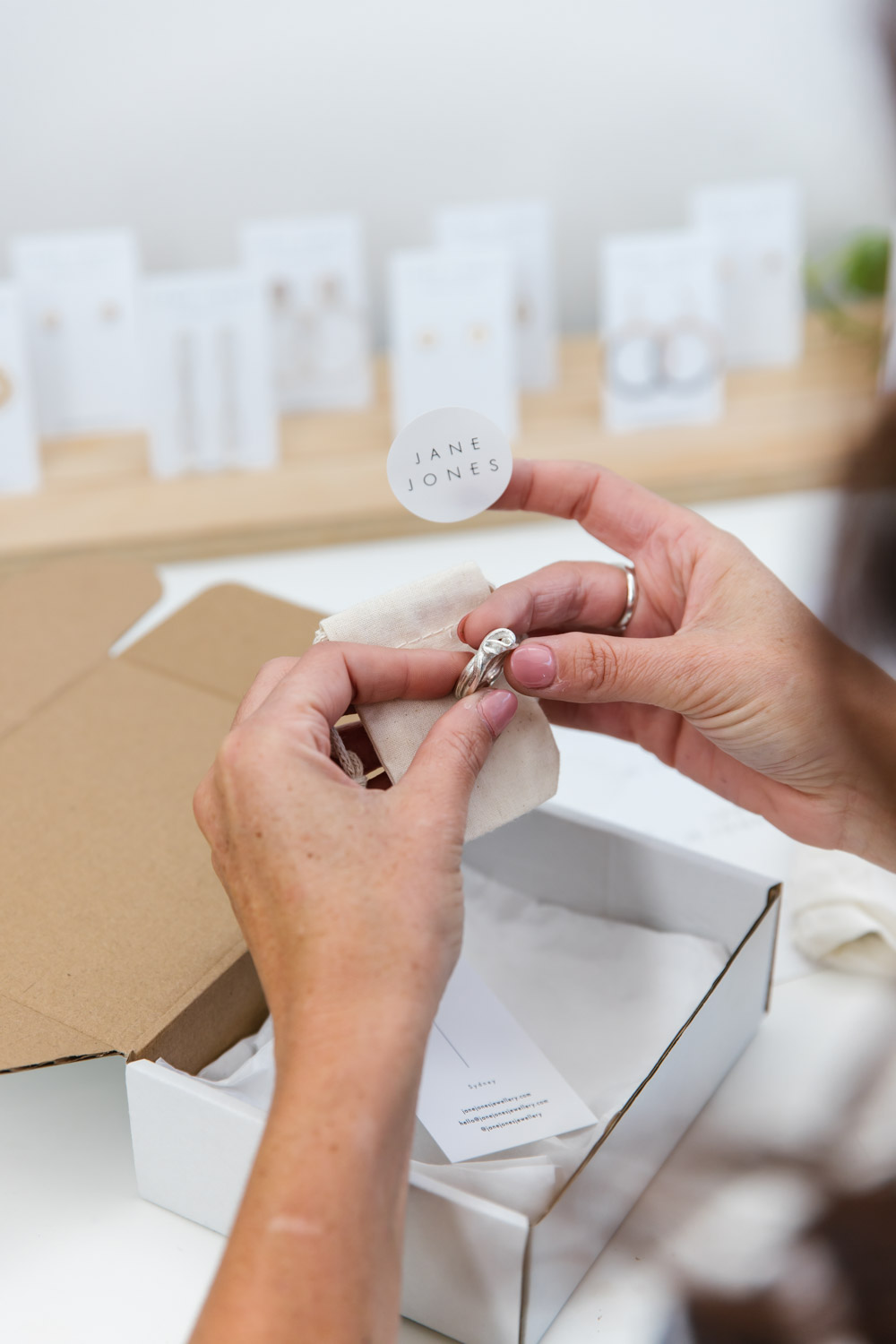 A jeweller packages up a silver ring in sustainable packaging ready to ship to the customer