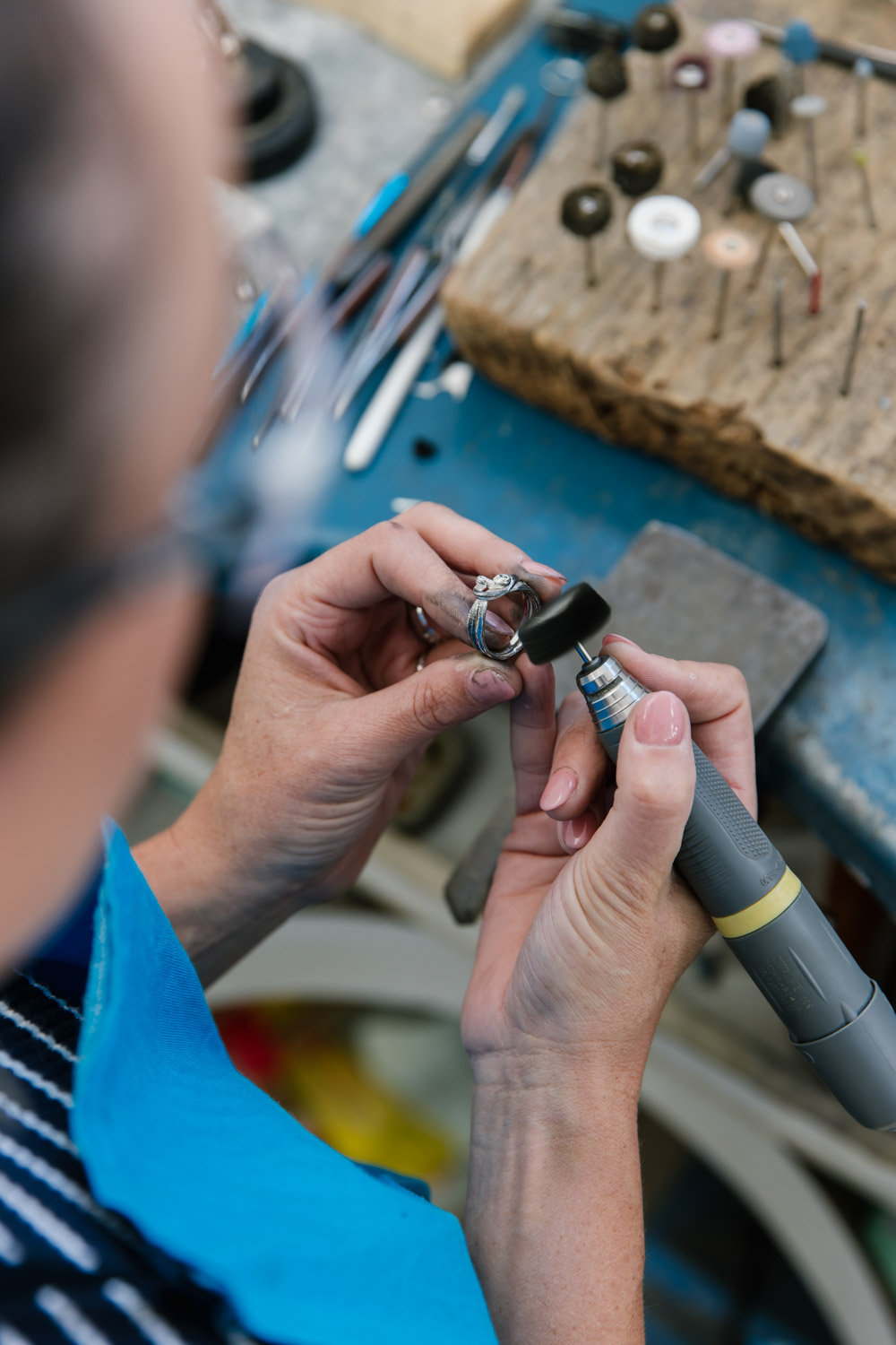 A jeweller polishes a sterling silver ring at her workbench