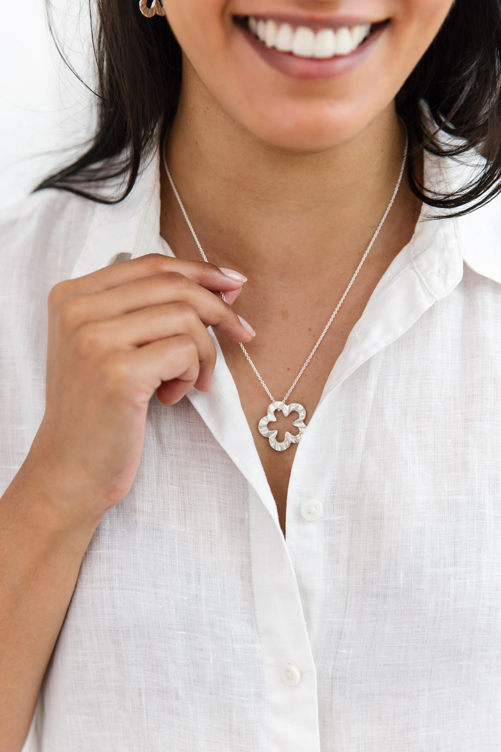 Woman wearing a sterling silver necklace with a delicate chain and a daisy design