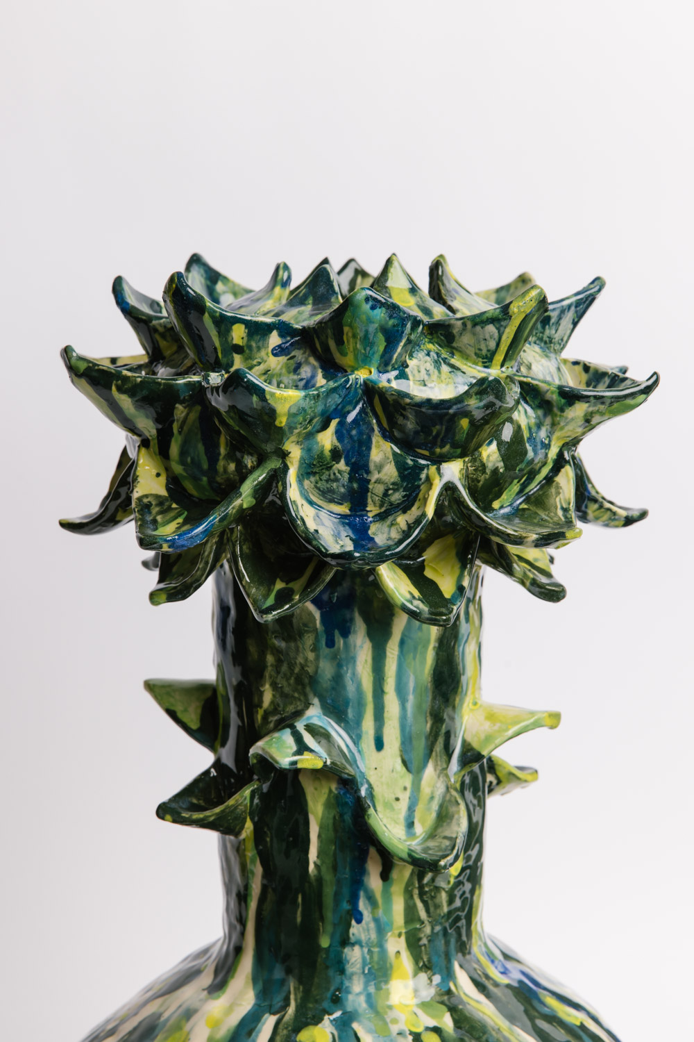 Detailed close up of large hand built ceramic vessel emulating a flower with dark green, yellow and blue painted underglazes, by Susan Buret, photo by Samee Lapham