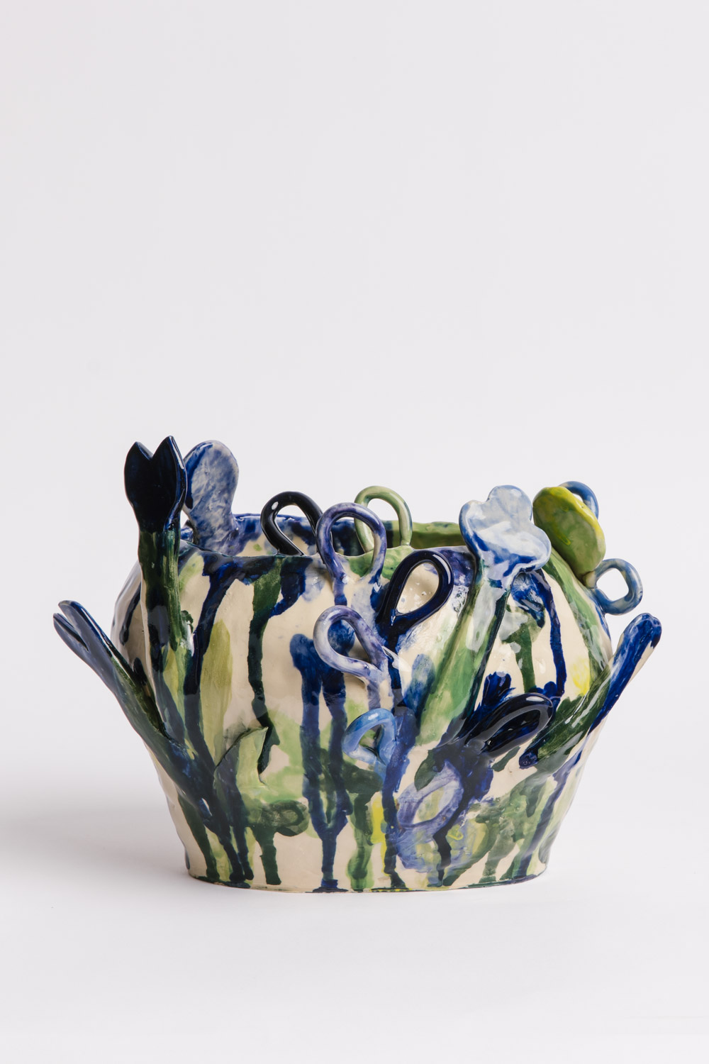Hand built ceramic vase with attached flower shapes to the surface and painted in expressive underglazes in greens and blues, by Susan Buret, photo by Samee Lapham