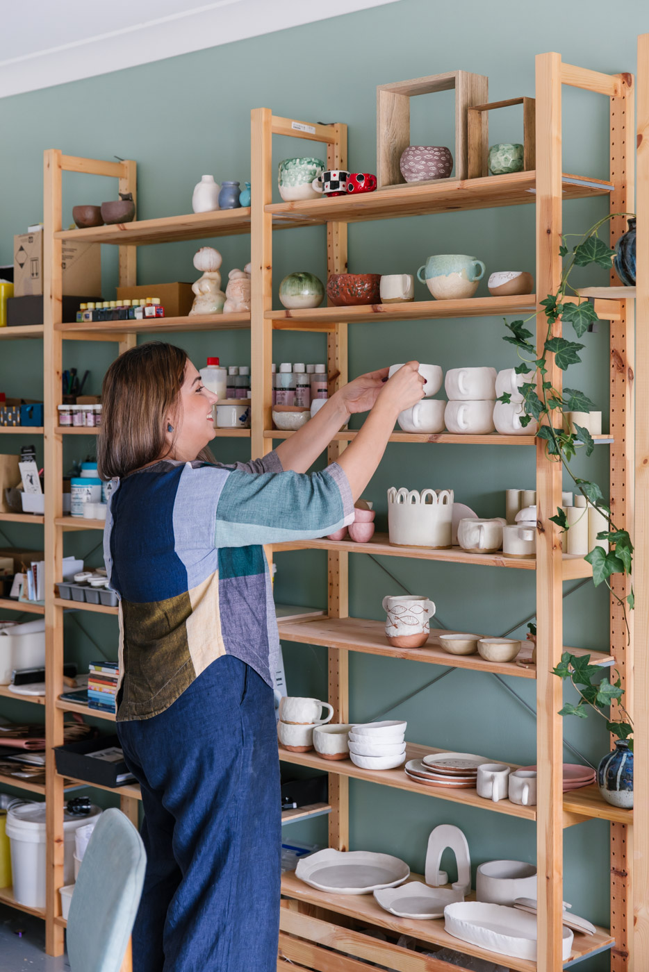 Soraya sorts the shelves of ceramic bisque fired pieces in her home studio